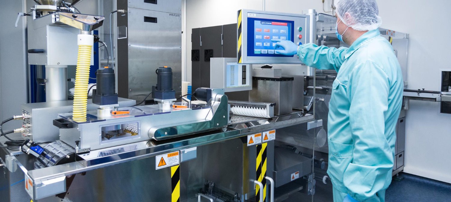 pharmacy industry factory man worker protective clothing sterile working conditions operating pharmaceutical equipment